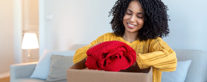 woman packing clothes into a box. Picture is for an article on where to donate clothes on Staten Island